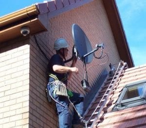 Warren Benskin on rooftop installing satellite dish